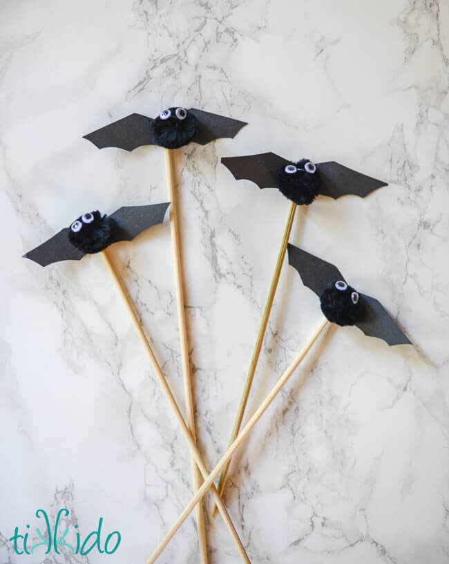 Bamboo skewers topped with cute bats made from pom poms, black paper, and googly eyes.