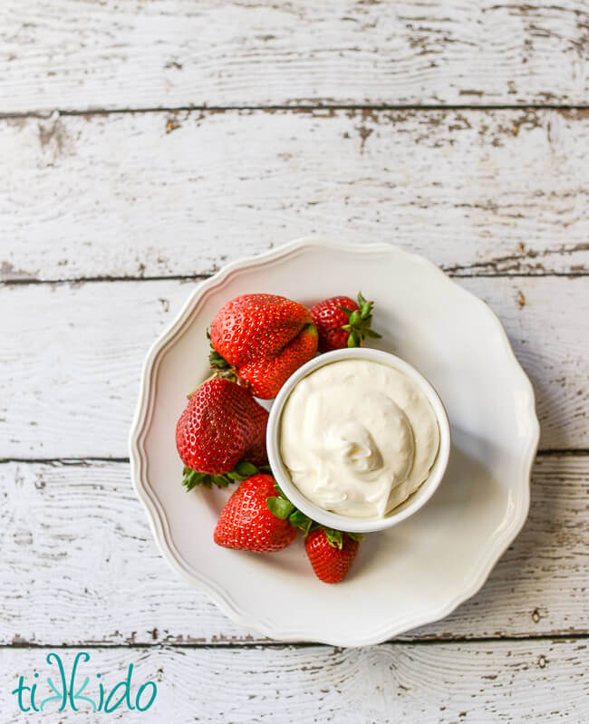 Easy fruit dip in a white bowl, surrounded by fresh strawberries.