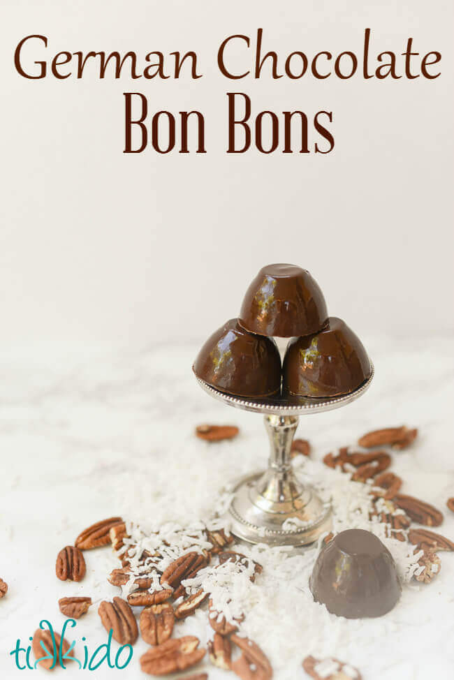 Chocolate bon bons on a small metal serving stand, with coconut and pecans scattered around base.