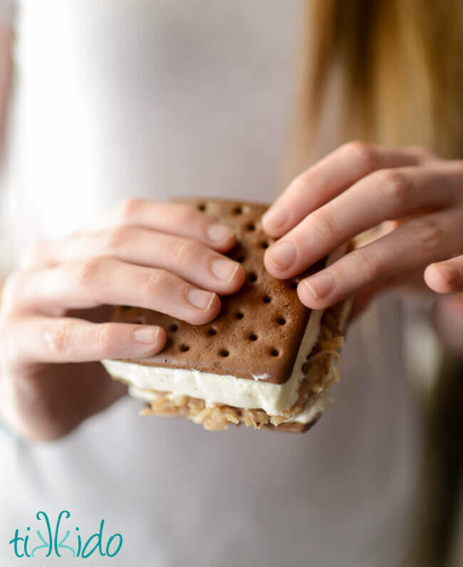 Hands holding an ice cream sandwich stuffed with german chocolate cake filling.