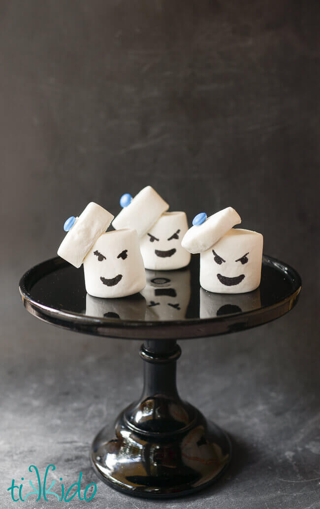 Three Stay Puft Marshmallow Treats on a black cake stand on a chalkboard background.