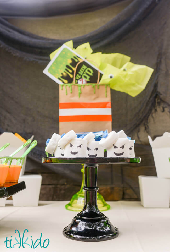 Ghostbusters Stay Puft Marshmallow Treats on a black cake stand on the dessert table at a Ghostbusters Halloween party.