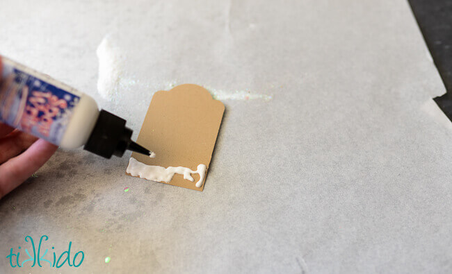 gingerbread gift tag being decorated with white puff paint.