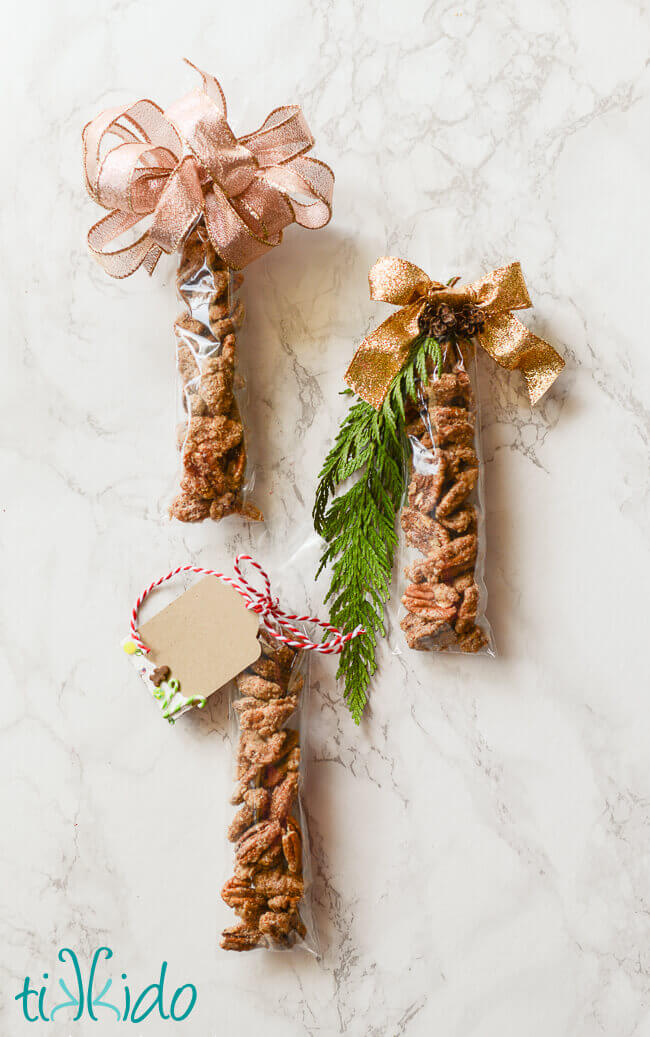 Gingerbread spiced candied pecans packaged for gift giving, in long, narrow cellophane bags, and tied with ribbon.