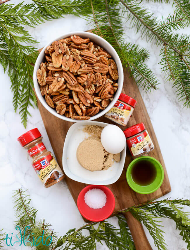 Ingredients for Gingerbread Spiced Candied Pecans on a wooden cutting board.