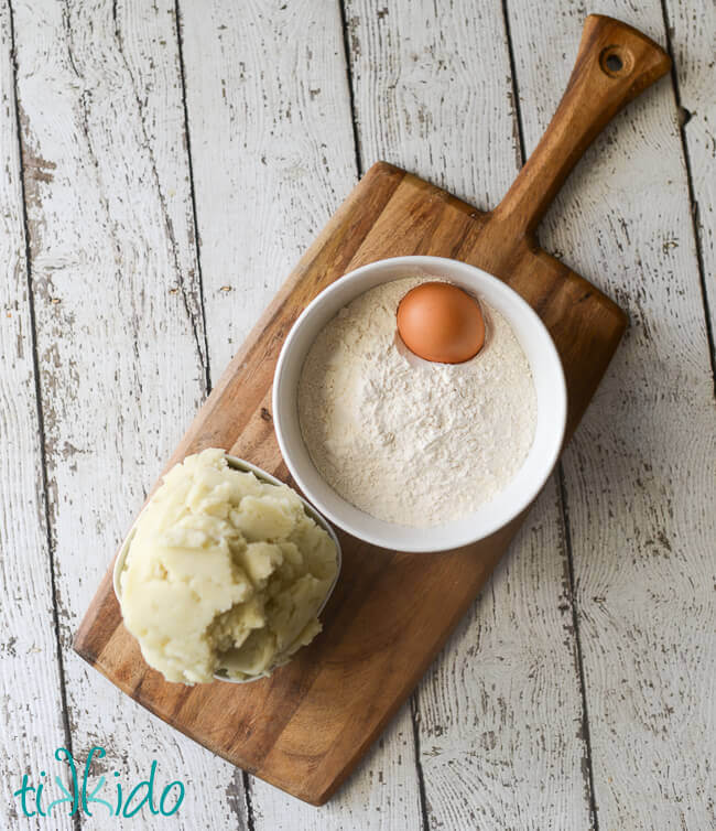 Potato gnocchi recipe ingredients on a wooden cutting board.