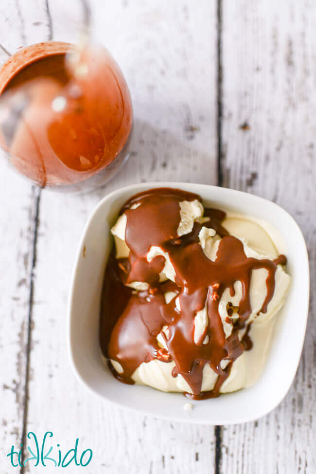 Peanut butter chocolate magic shell ice cream topping on vanilla ice cream in a white bowl on a white background.