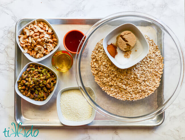 Ingredients for homemade granola recipe measured out and sitting on a baking sheet.