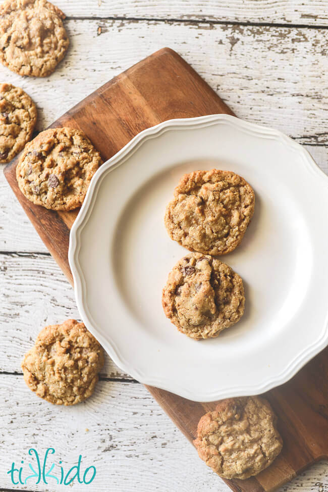 oatmeal chocolate chip cookies on a white plate on a wooden cutting board.