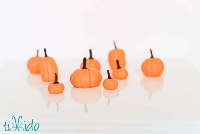 Gum Paste Pumpkins on a white reflective surface.