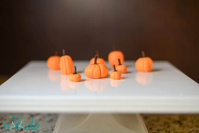 Gum paste pumpkins on a square white cake plate.