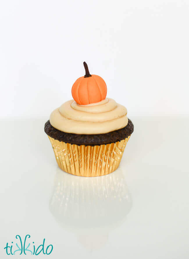 Cupcake decorated with a Gum Paste Pumpkin on a white background.