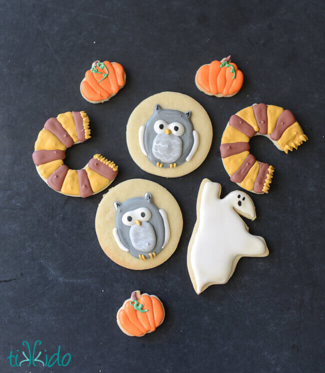 Harry potter scarf, owl, pumpkin, and Nearly Headless Nick ghost sugar cookies on a black chalkboard background.