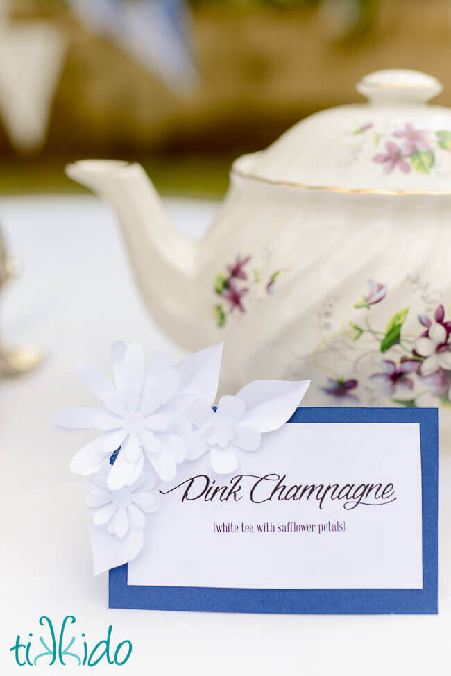 Table Tent for a tea party embellished with miniature white paper flowers.