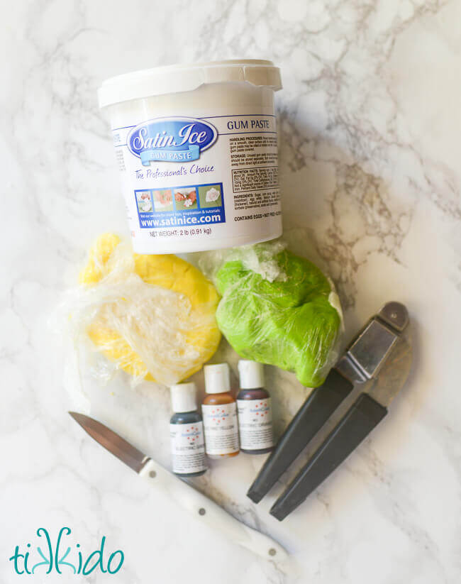 Ingredients and equipment for homemade sprinkles on a white marble background.