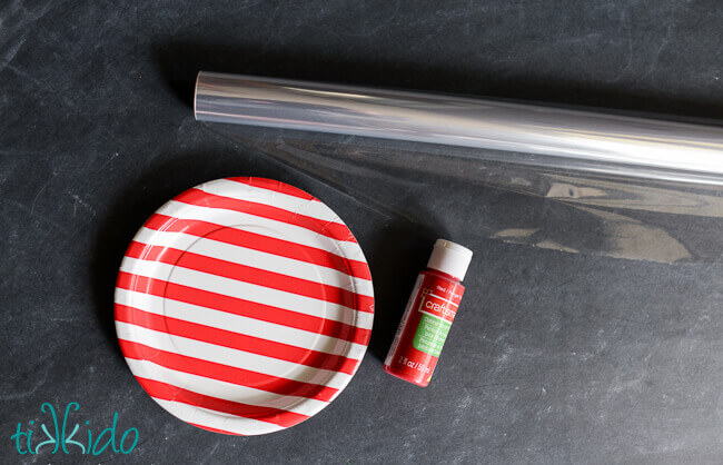 paper plate, cellophane wrap, and red paint on a black chalkboard background.