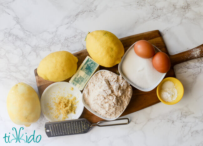 Ingredients for lemon muffins on a wooden cutting board.