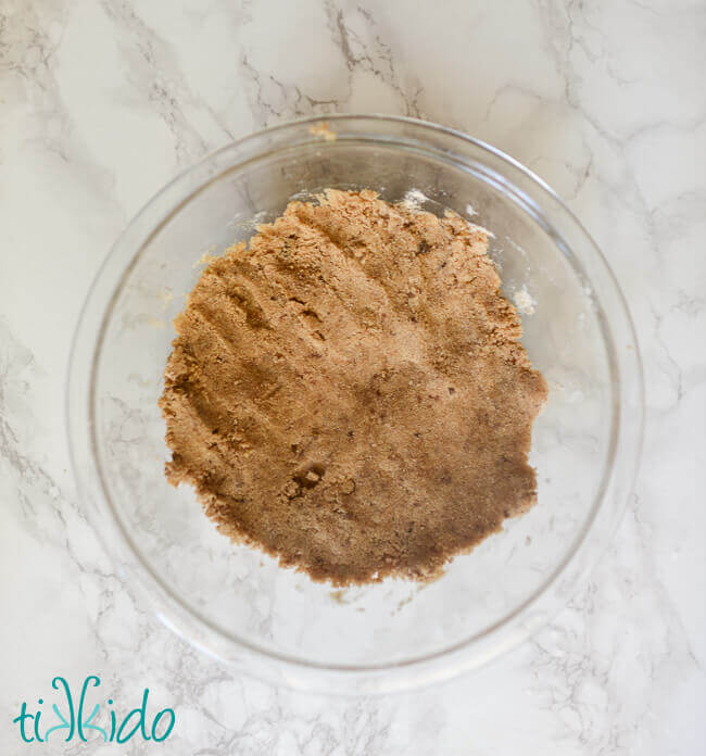 Streusel crumb topping in a clear pyrex bowl on a white marble surface.