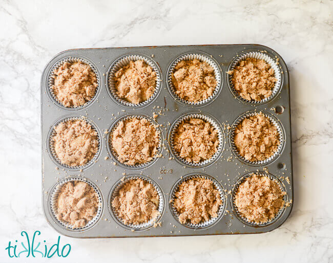 Uncooked lemon muffins in a muffin tin on a white marble background