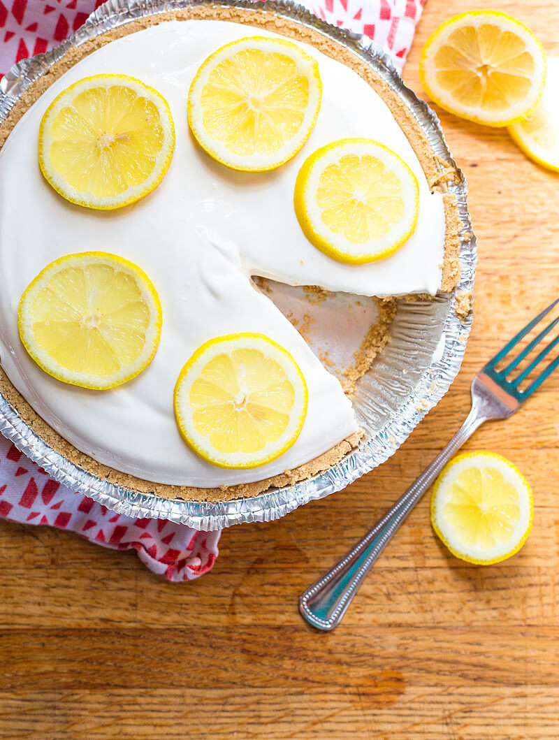 Frozen lemonade pie with graham cracker crust in a disposable pie tin, with one slice of the pie removed.