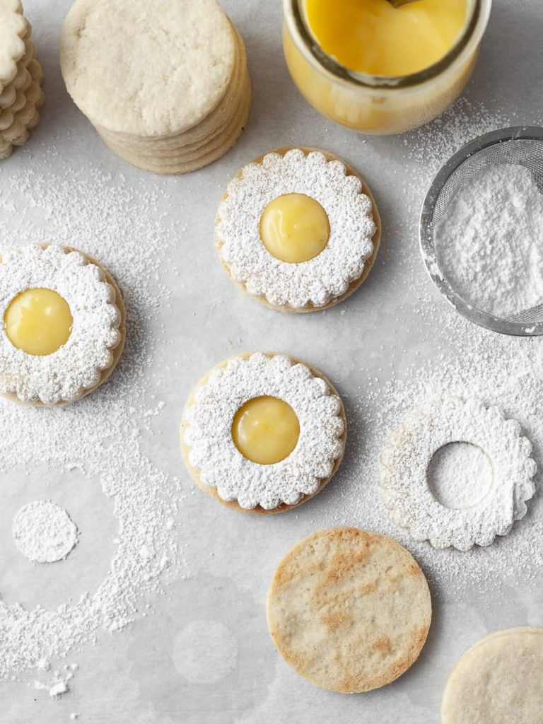 Gluten free lemon linzer cookies dusted with powdered sugar and filled with lemon curd.