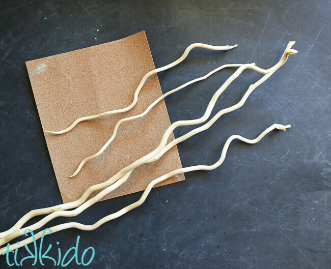 Currly willow sticks and sanding paper on a black chalkboard background