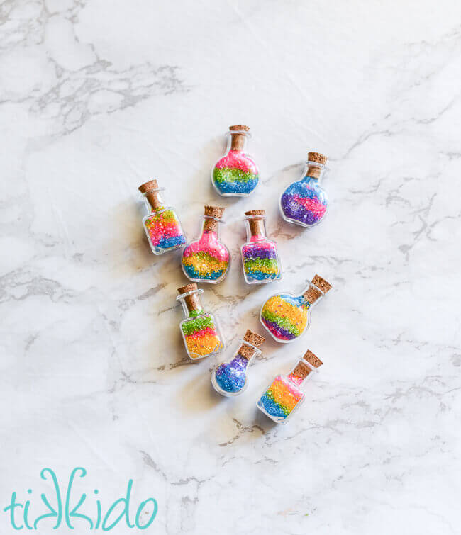 Miniature potion bottles filled with layers of different colors of colored sugar.