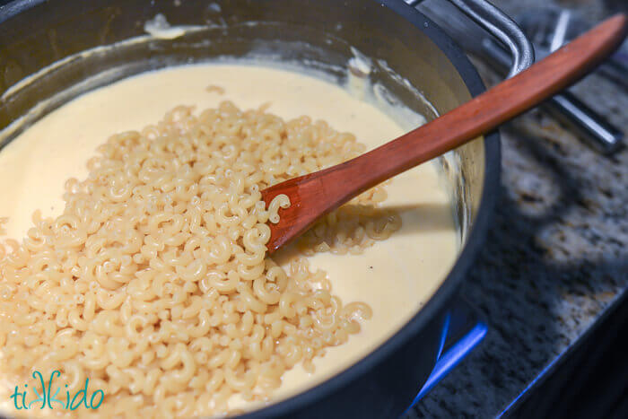 Partially cooked macaroni being mixed in a cheese sauce to make Baked Macaroni and Cheese.