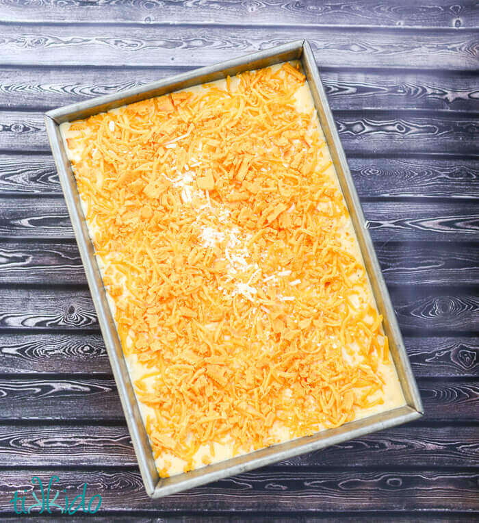 Shredded cheese sprinkled over the top of baked mac and cheese ready to put in the oven.
