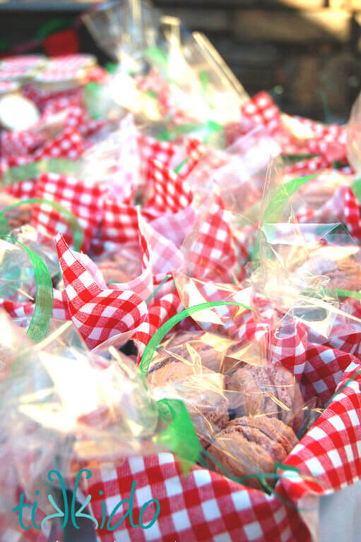 Strawberry macarons in red and white gingham lined green plastic strawberry baskets at the Strawberry Picnic birthday.