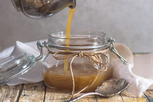 Maple caramel ice cream sauce being poured into a glass jar.