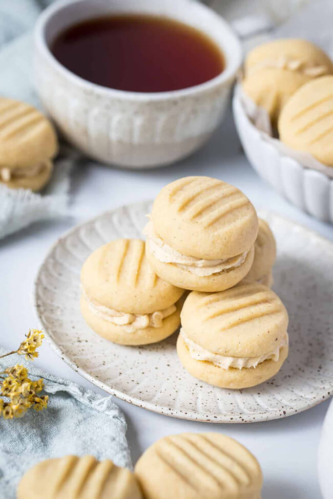 Melting Moments whipped shortbread cookies, an eggless cookie recipe, on a plate in front of a cup of tea.