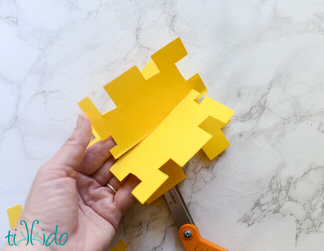 Yellow paper being cut into life sized pixelated Minecraft flowers for a Minecraft birthday party.