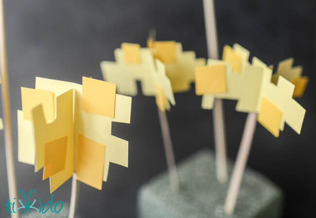 Yellow paper being cut into life sized pixelated Minecraft flowers for a Minecraft birthday party.