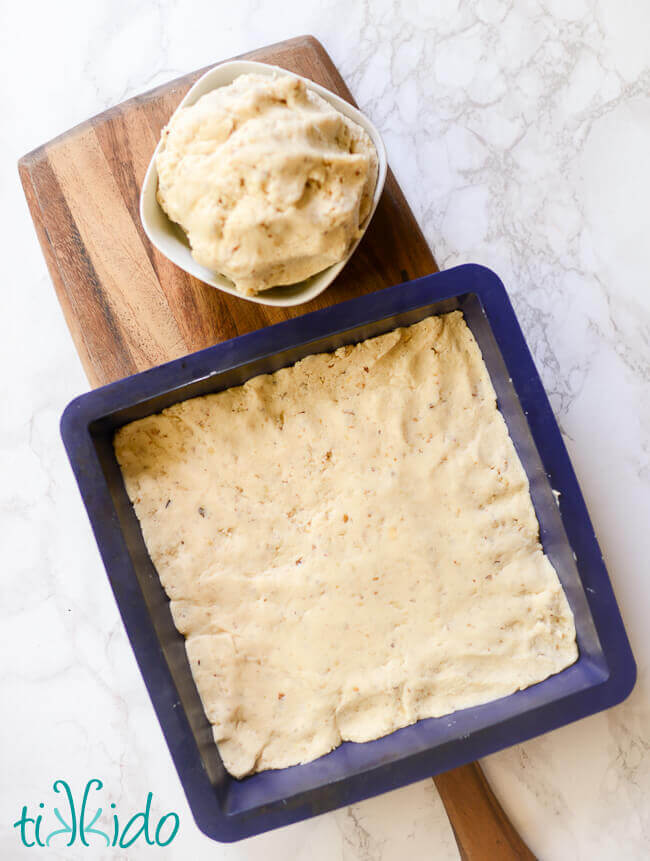 Raspberry crumble bar cookie dough in silicone pan on a wooden cutting board.