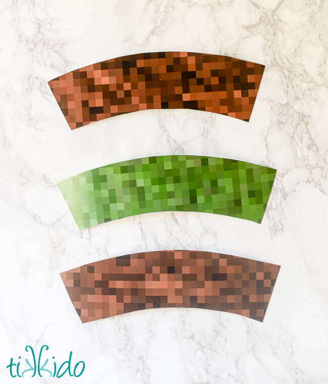Mincecraft cupcake wrappers cut out of printable Minecraft paper on a white marble background.