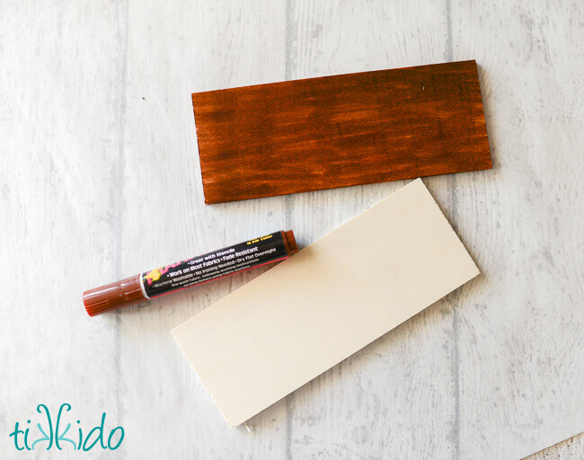 Two small rectangles of wood, one stained brown with a brown marker.