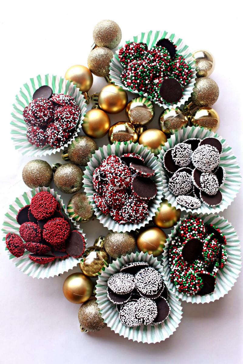Cupcake liners filled with homemade nonpariel candies surrounded by Christmas ornaments.