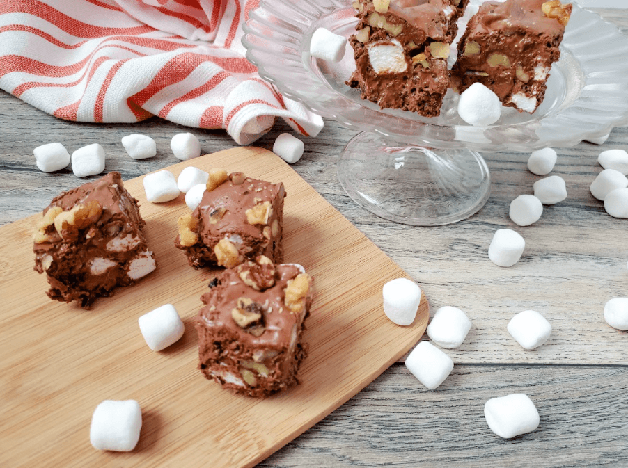 Old fashioned rocky road fudge on a wooden cutting board, surrounded by mini marshmallows.