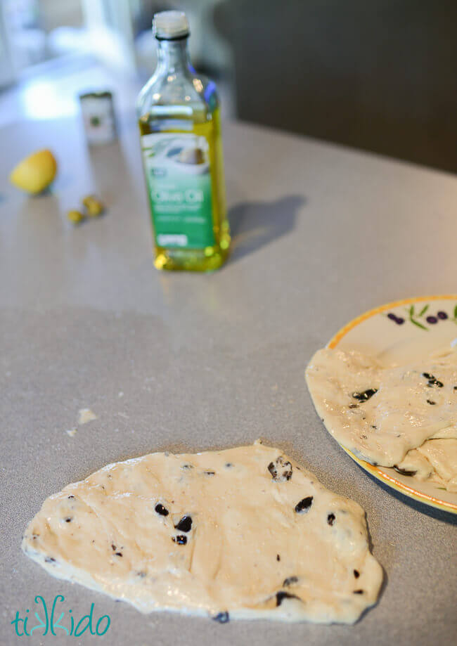 Bread dough coated in olive oil and shaped into a flat disk, ready to be grilled.