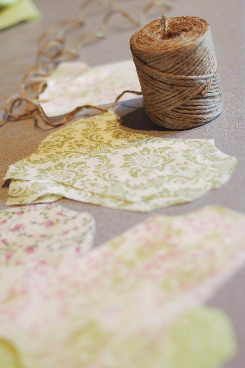 Fabric cut into onesie shapes for the Baby Shower Garland, next to a spool of twine.