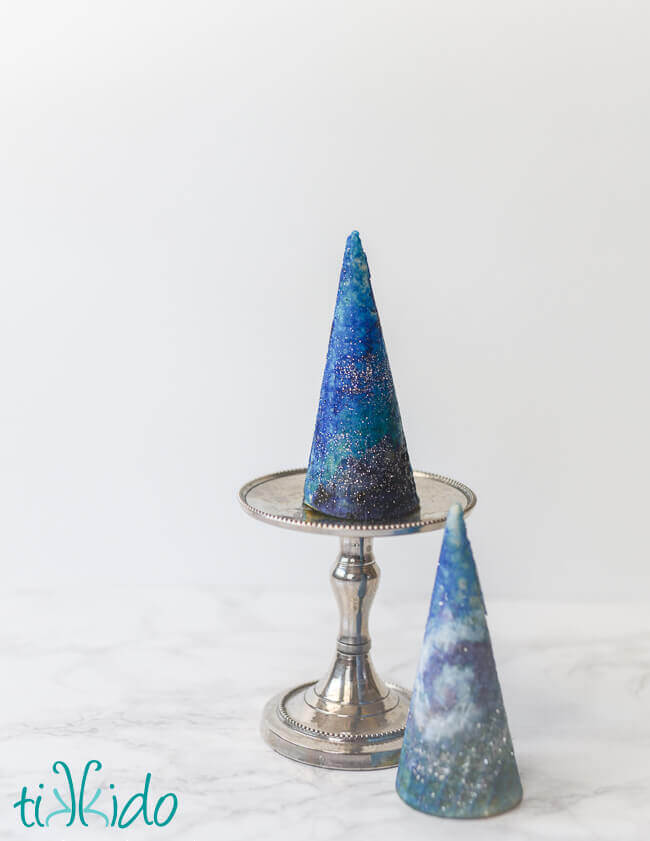  Two ice cream cones painted with food coloring like a swirling galaxy with silver disco dust stars.