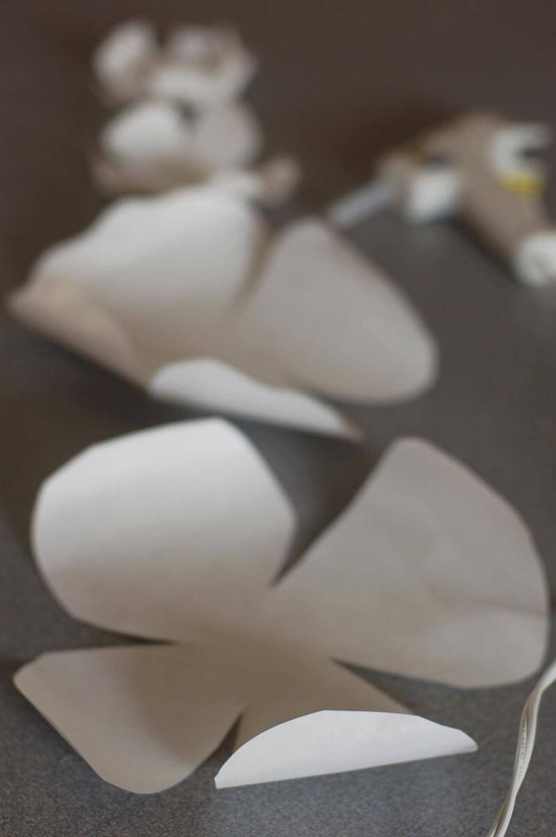 Plain white paper cut into graduated flower shapes, with the edges of the petals curled up slightly.