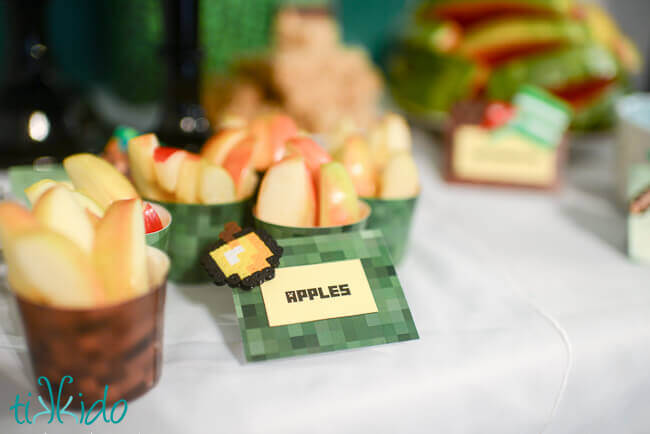Nut cups wrapped in Minecraft paper and full of slices of apples at a Minecraft birthday.