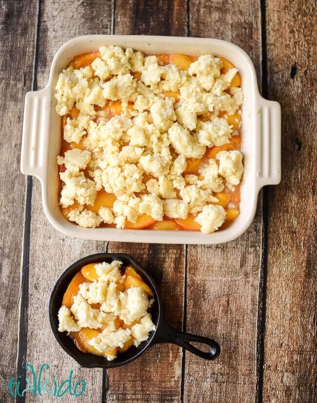 Unbaked peach cobbler in a baking dish on a wooden background.