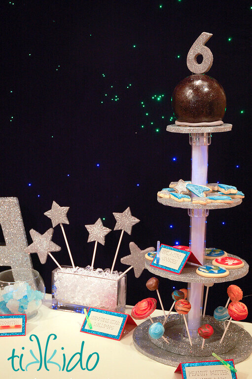 Four tiered serving tray with a glowing blue center column, with space themed treats arranged on the levels.