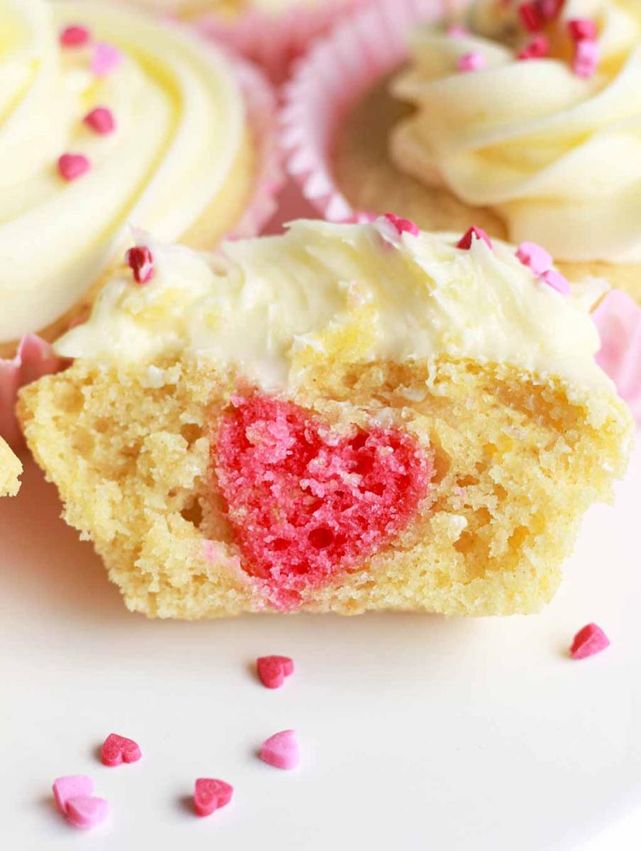 Vanilla cupcake with a pink heart baked inside for valentine's day.