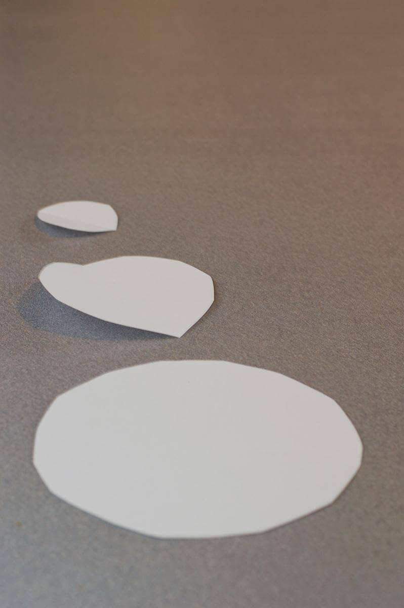 Plain white paper cut into three circles of graduated sizes, sitting on a counter.