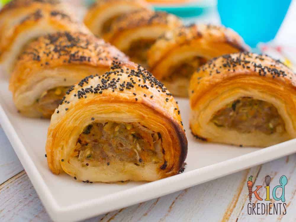 Pork, apple, and vegetable sausage roll appetizers on a white serving tray.