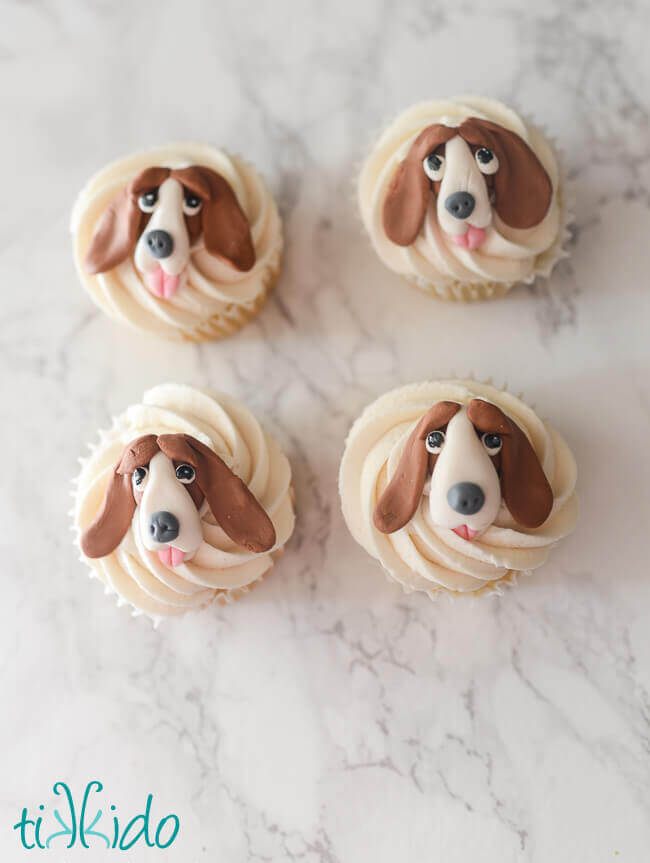 Four cupcakes decorated with gum paste hound dogs